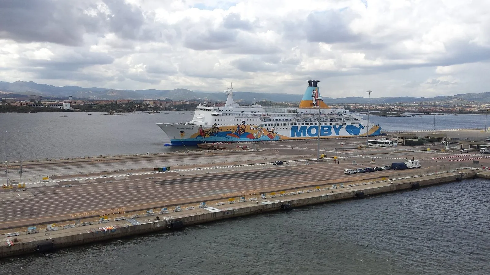 Traghetto ormeggiato alla banchina del porto di Olbia, con le colline della Gallura sullo sfondo