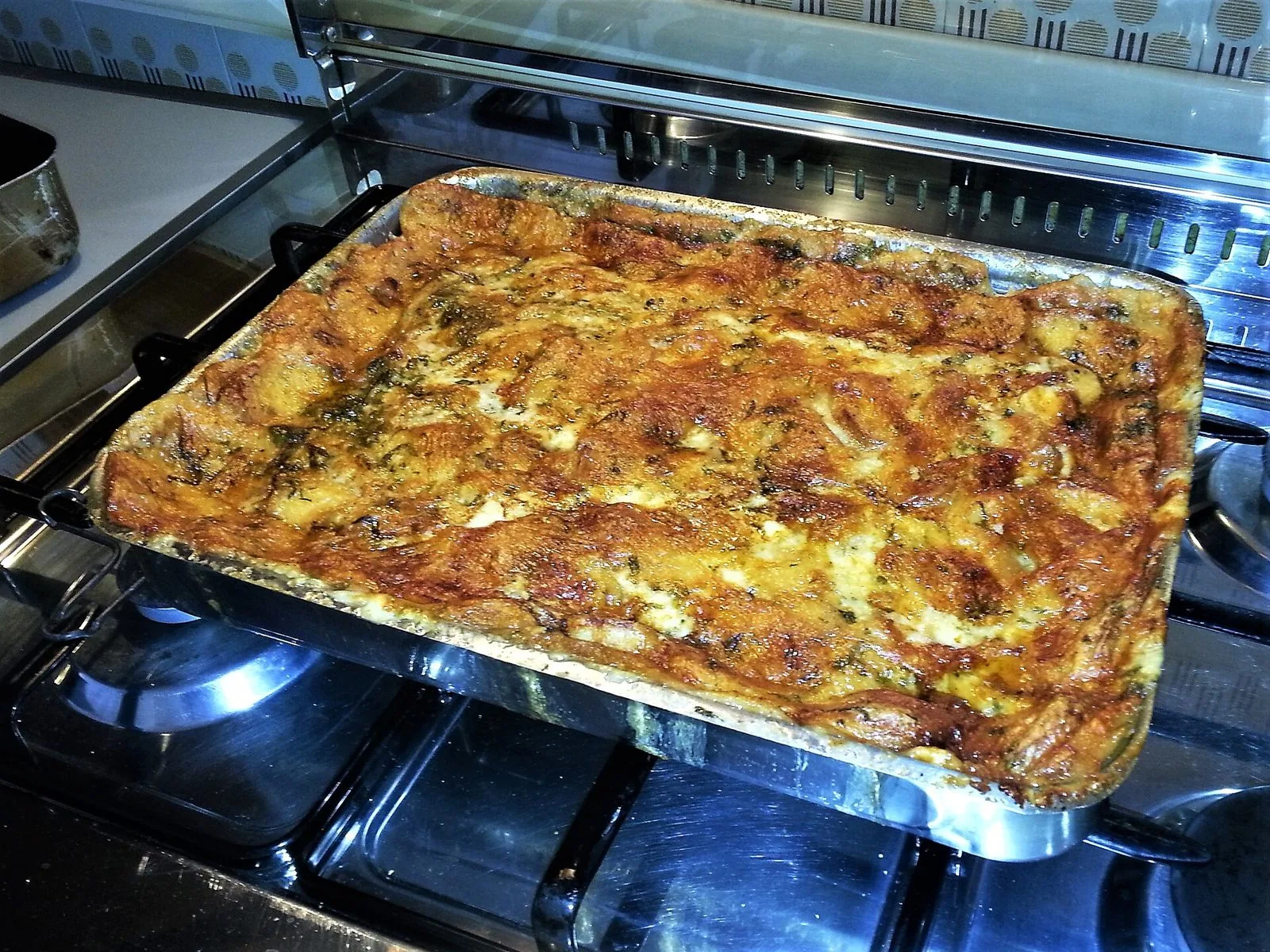 Teglia di zuppa gallurese appena sfornata, con la crosta dorata di formaggio e prezzemolo